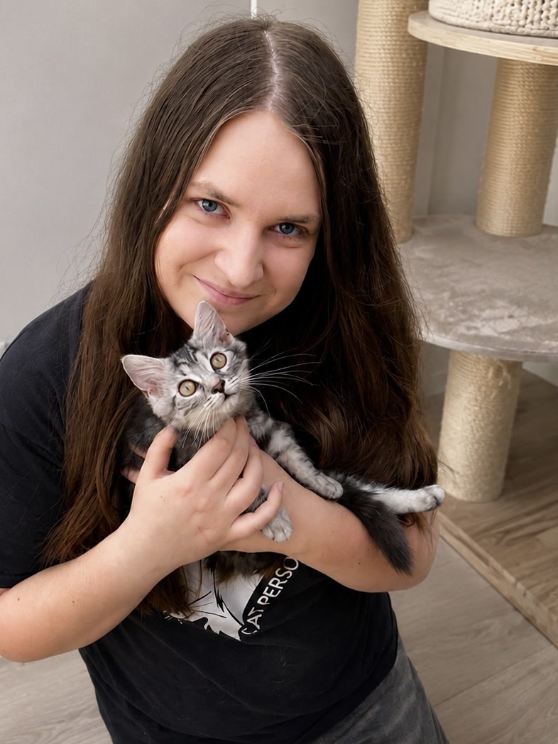 Lisa Grebenteuch hält eine junge grau-weiße Katze in einem hellen Wohnzimmer im Arm